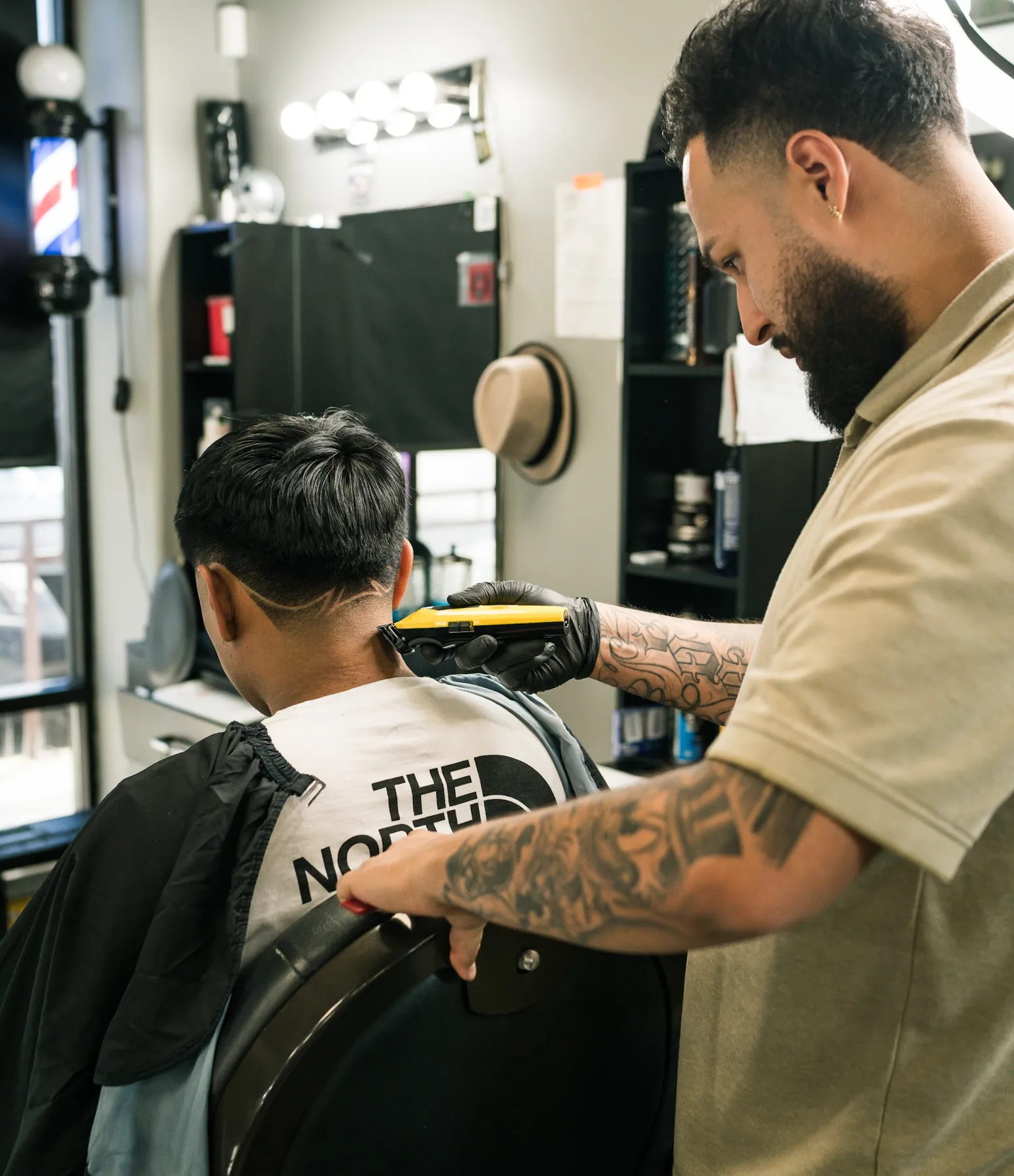 Barber shaping a fade on a client inside VIP Barber Lounge Aurora